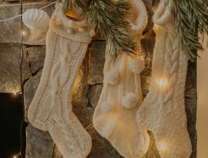 Three handmade white christmas stockings hanging over the fire