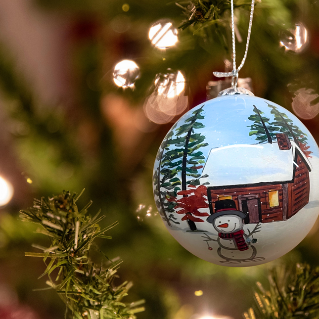 Snowman and Deer Next to a Snowy Cabin